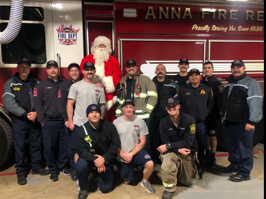 Firefighters and a Santa posing in front of a fire engine