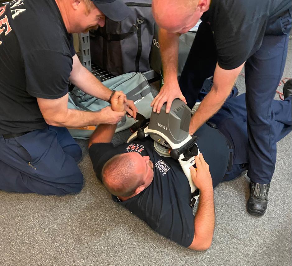 Firefighters using medical equipment on the chest of  a man laying down